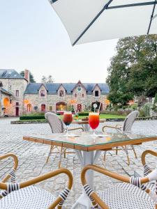a table with chairs and drinks on a patio at Hôtel & Spa de La Bretesche in Missillac