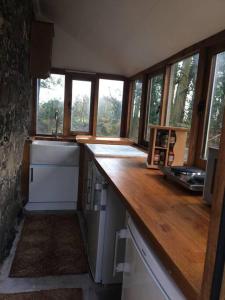 a kitchen with a wooden counter top and windows at The Studio, Trelugga in Helston