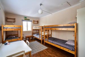 a room with three bunk beds and a table at Hovra Vandrarhem in Korskrogen