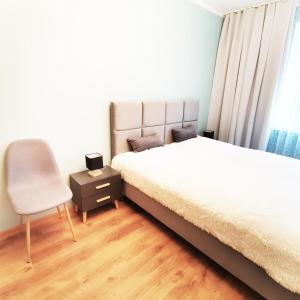 1 dormitorio con 2 camas y 1 silla en Apartament Piernikowe Serce, en Toruń