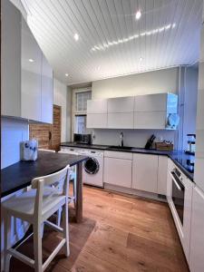 a kitchen with white cabinets and a table and a dishwasher at Uniikki&Upea Helmi ydinkeskustassa in Tampere