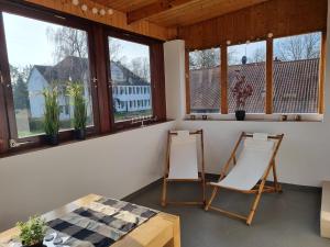 Duas cadeiras e uma mesa num quarto com janelas em Ferienwohnung Irina em Zülpich