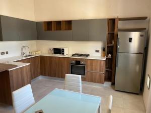 a kitchen with a table and a stainless steel refrigerator at Sliema Central 2-Bedroom on a Quiet Street, Near Valletta by Malta Weekend in Sliema