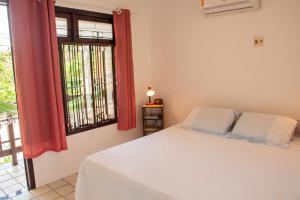 a bedroom with a white bed and a window at Apartamento a 400 metros da Praia do Frances-AL in Marechal Deodoro
