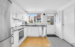 a white kitchen with white appliances and a window at Two-Bedroom Holiday Home In Tranekar in Lohals