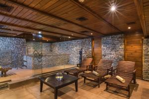 a room with chairs and a table and a stone wall at Mura Hotel in Bansko