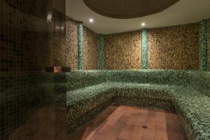 a bathroom with green tiled walls and a tub at Mura Hotel in Bansko
