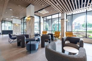 a lobby with chairs and tables and windows at Owen House by Habyt in Singapore