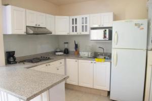 La cuisine est équipée de placards blancs et d'un réfrigérateur blanc. dans l'établissement Catana N12, à Acapulco
