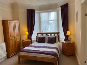 a bedroom with a bed with purple sheets and a window at The Laurels in Blackpool