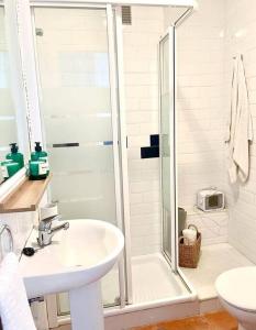 biała łazienka z prysznicem i umywalką w obiekcie El Gato Gris w mieście Conil de la Frontera