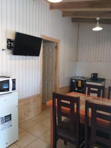 a kitchen with a table and a television on the wall at Hosteria y Cabañas Rucantu in Freire