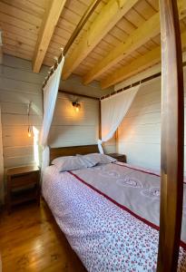a bed in a room with a wooden ceiling at Le Chalet du Moulin in Brousses-et-Villaret