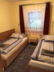 1 dormitorio con 2 camas y ventana en Százszorszép Vendégház en Mezőkövesd