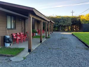 un porche de una casa con sillas rojas en Hosteria y Cabañas Rucantu, en Freire