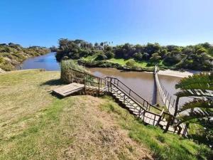 una escalera que conduce a un río con un puente en Los Abuelos, en La Coronilla