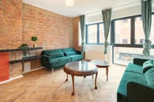 a living room with green furniture and a brick wall at Charming and Spacious Antwerp City Center Apartments in Antwerp
