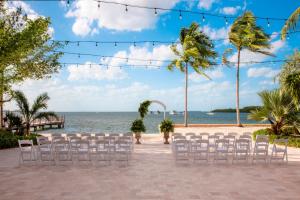 an outdoor wedding ceremony on the beach with white chairs at Beachside Resort & Residences in Key West