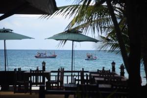 dos barcos en el océano con mesas y sombrillas en Coconut House Resort, en Koh Samui 