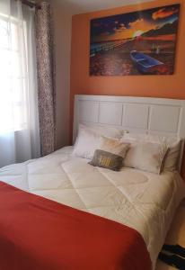 a large white bed with a painting on the wall at Stellar 1-bedroom apartment in Madaraka Estate, Nairobi in Nairobi