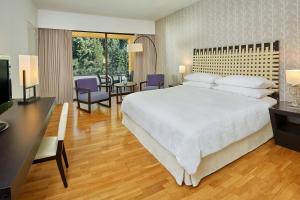 a bedroom with a large bed and a dining room at Sheraton Rhodes Resort in Ixia
