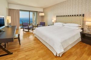 a bedroom with a large white bed and a desk at Sheraton Rhodes Resort in Ixia
