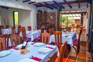 a dining room with white tables and wooden chairs at Hotel Casona del Virrey in Moniquirá