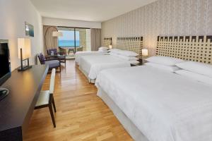 a hotel room with three beds and a desk at Sheraton Rhodes Resort in Ixia