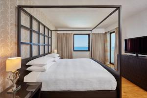 a bedroom with a large bed and a flat screen tv at Sheraton Rhodes Resort in Ixia