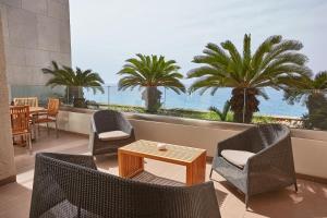 a patio with chairs and a table and a view of the ocean at Sheraton Rhodes Resort in Ixia