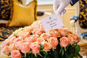 a person holding a sign over a bouquet of pink roses at Hotel Imperial, a Luxury Collection Hotel, Vienna in Vienna