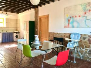 uma sala de jantar com uma mesa de vidro e cadeiras coloridas em La Almedina casa Bellavista em Cazorla