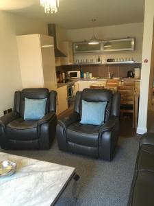 a living room with two chairs and a kitchen at Silverhill House Apartment in Enniskillen