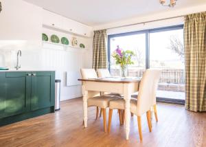 cocina y comedor con mesa y sillas en Gardener's Cottage en Alnwick