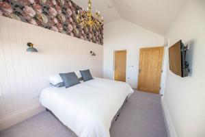 1 dormitorio con cama blanca y almohadas azules en Gardener's Cottage en Alnwick