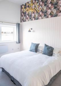 a bedroom with a large white bed with blue pillows at Gardener's Cottage in Alnwick