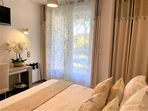 a bedroom with a bed and a window with curtains at Hôtel Le Méditerranée in Hyères