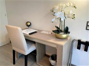 a desk with a chair and a vase of flowers at Hôtel Le Méditerranée in Hyères