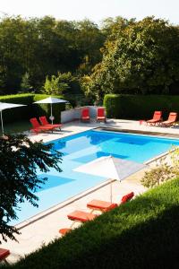 a swimming pool with red chairs and umbrellas and chairs at Cottages De La Bretesche in Missillac +30 photos