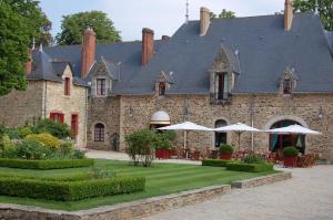a large brick building with umbrellas in a courtyard at Cottages De La Bretesche in Missillac