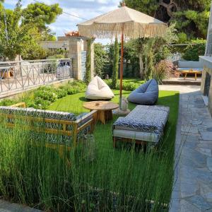 un giardino con tavolo, sedie e ombrellone di Augoustinos - Sea Side Luxury Apartments a Artemida