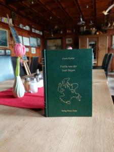 a book on a table with a flower in a vase at Pension & Restaurant "Alte Schule" in Kluis