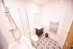 a white bathroom with a toilet and a shower at The Coach House in Alnwick +17 photos