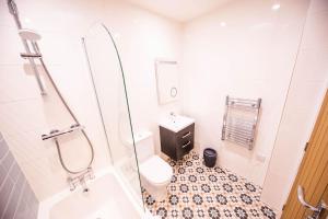 a white bathroom with a toilet and a shower at The Coach House in Alnwick