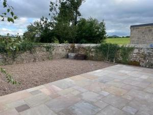 um jardim com uma parede de pedra e um pátio em The Kennelman 3 bedroom option em Alnwick