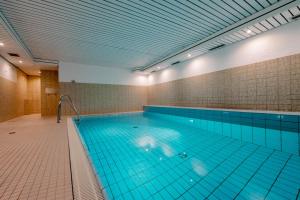 ein großer Swimmingpool mit blauen Fliesen an den Wänden in der Unterkunft Hüs Wüf im Haus Ornum in Westerland