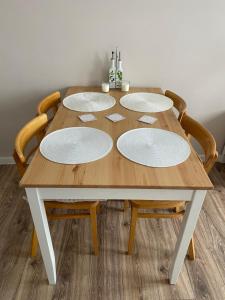 Apartament Jaskółka في سترونيش لونسكي: طاولة خشبية عليها اربعة اطباق بيضاء