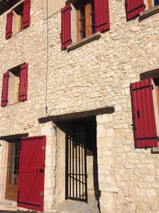 - un bâtiment en pierre avec des portes et des fenêtres rouges dans l'établissement LA MAISON D’ALICE, à Sault