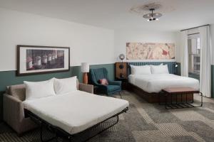 a hotel room with two beds and a chair at Hotel Forty Five, Macon, a Tribute Portfolio Hotel in Macon