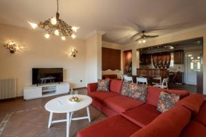 a living room with a red couch and a table at Phoceus Poolfront Grande Villa in Palaiá Fókaia